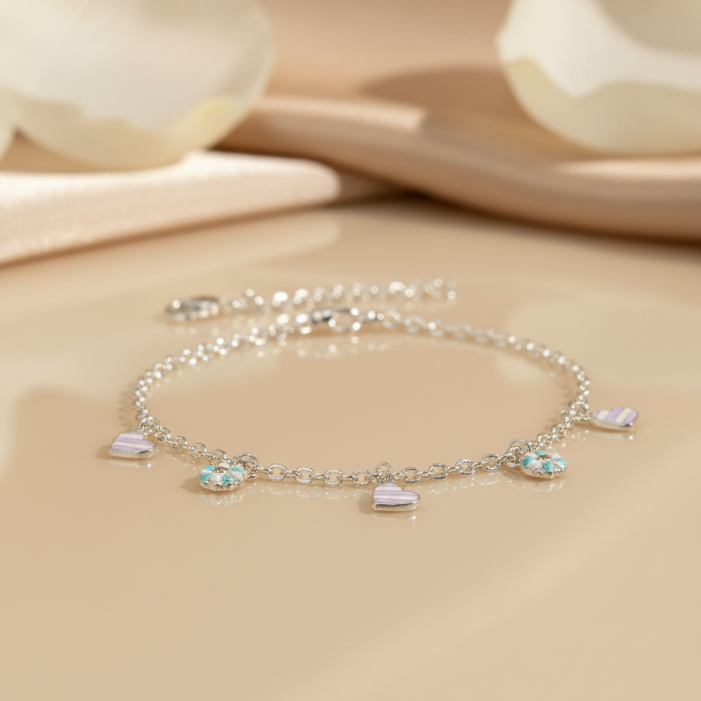 Silver bracelet with heart-shaped charms on a beige background