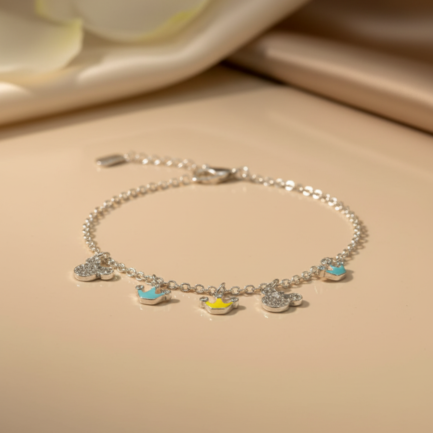 Silver bracelet with charms on a beige surface