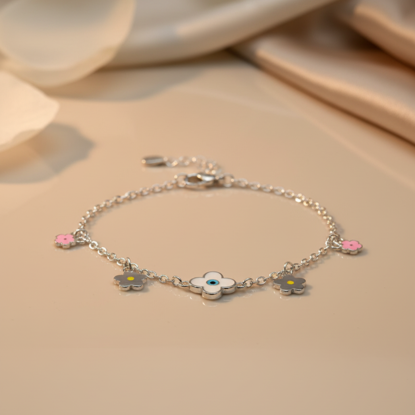 Silver bracelet with flower charms on a beige surface
