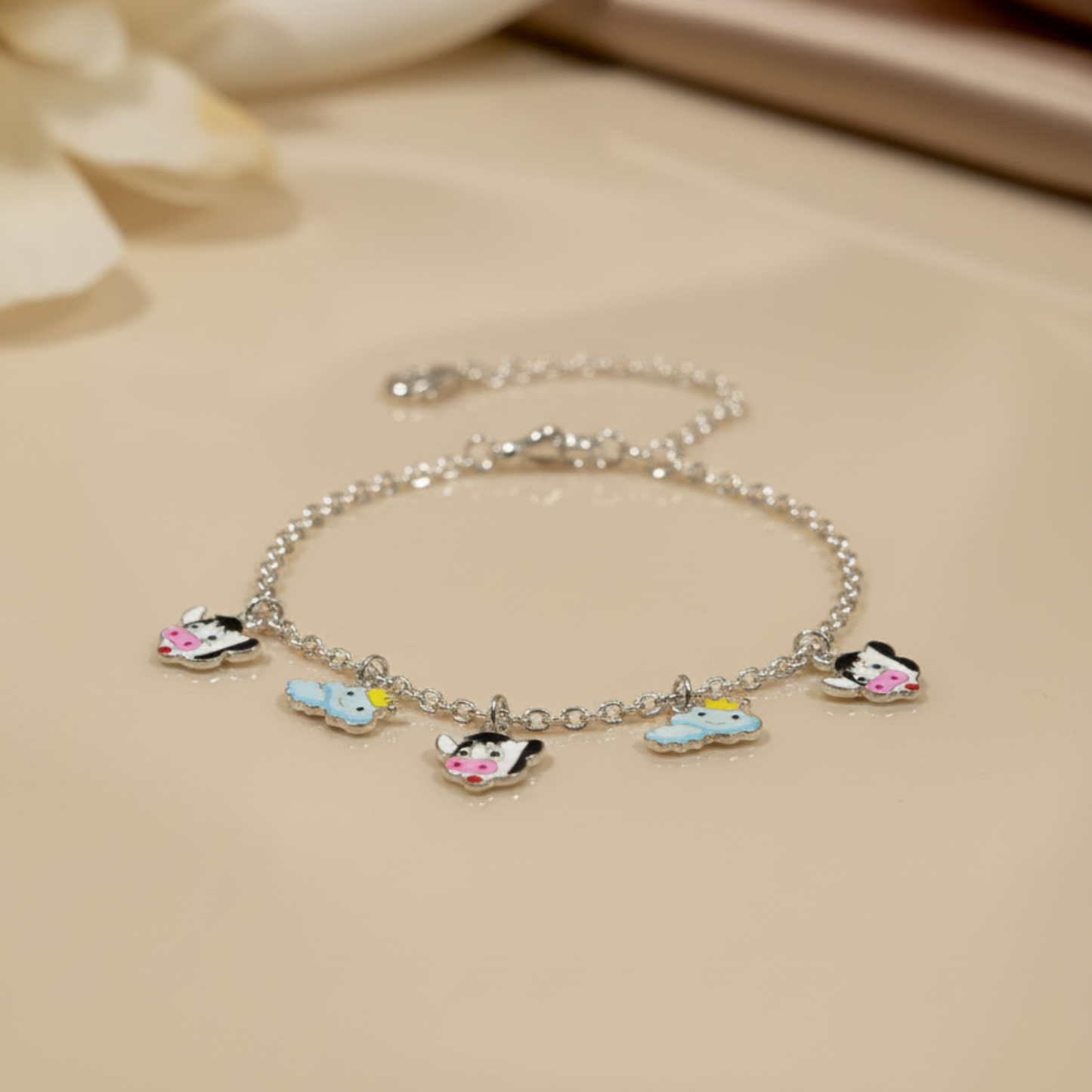 Silver bracelet with cartoon character charms on a beige background