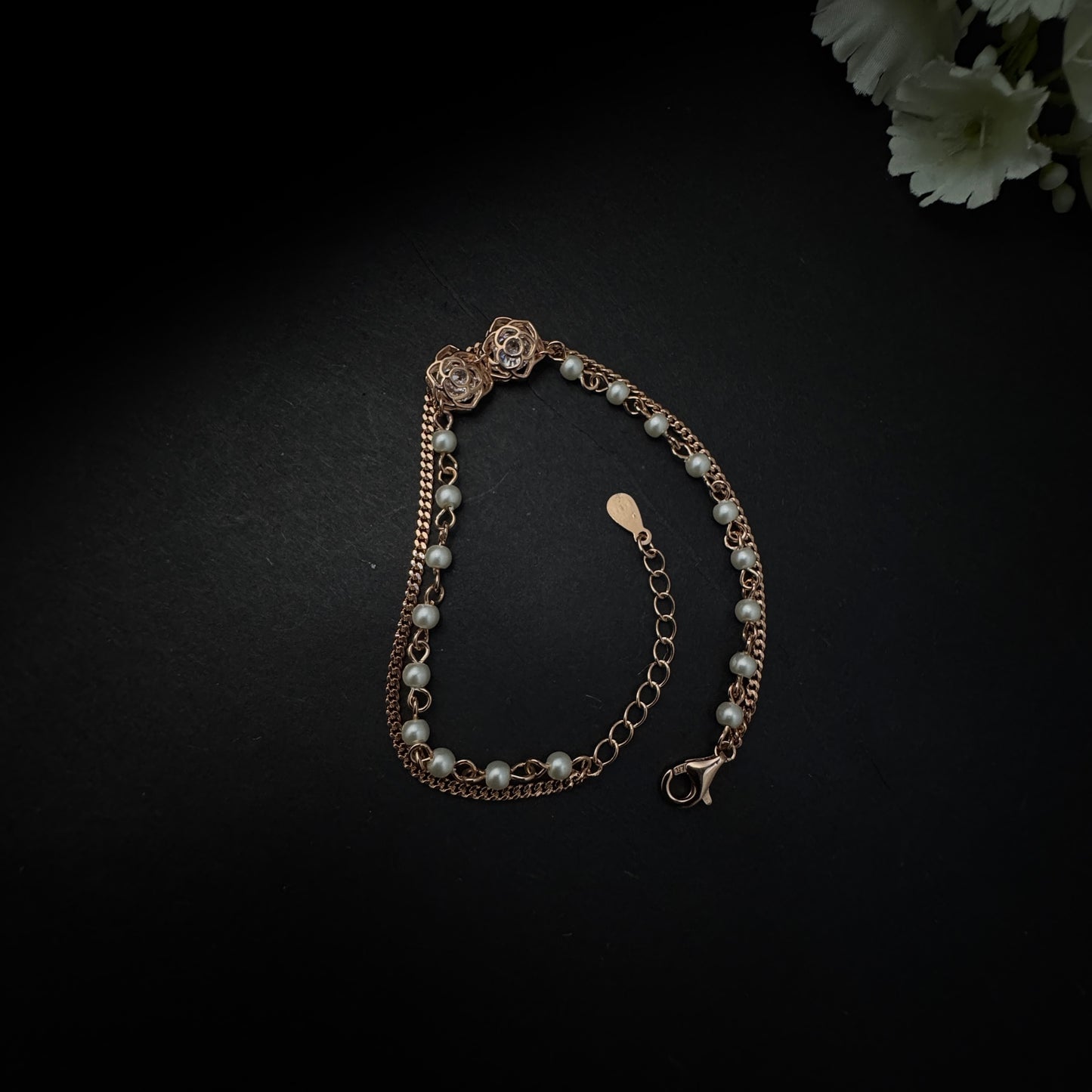 Pearl bracelet with gold chain on a dark background