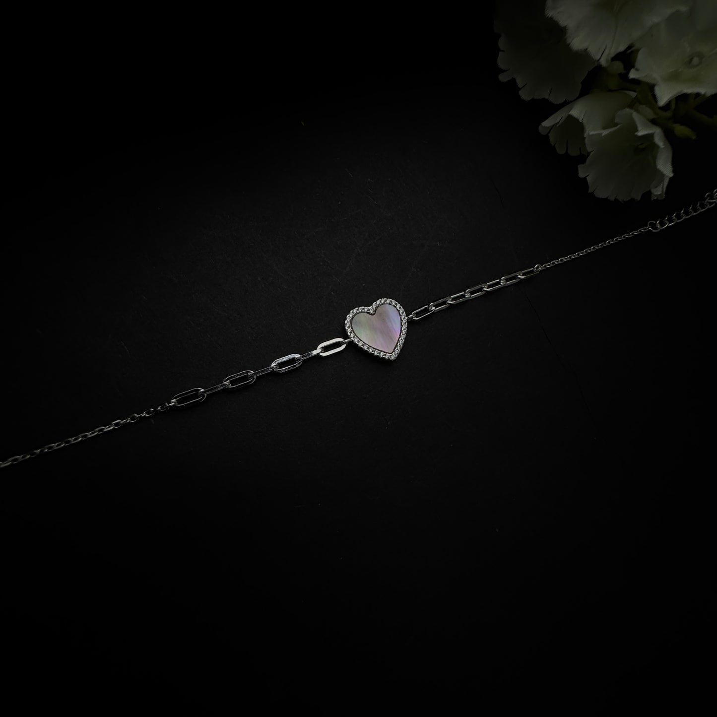 Silver bracelet with a heart-shaped charm on a black background