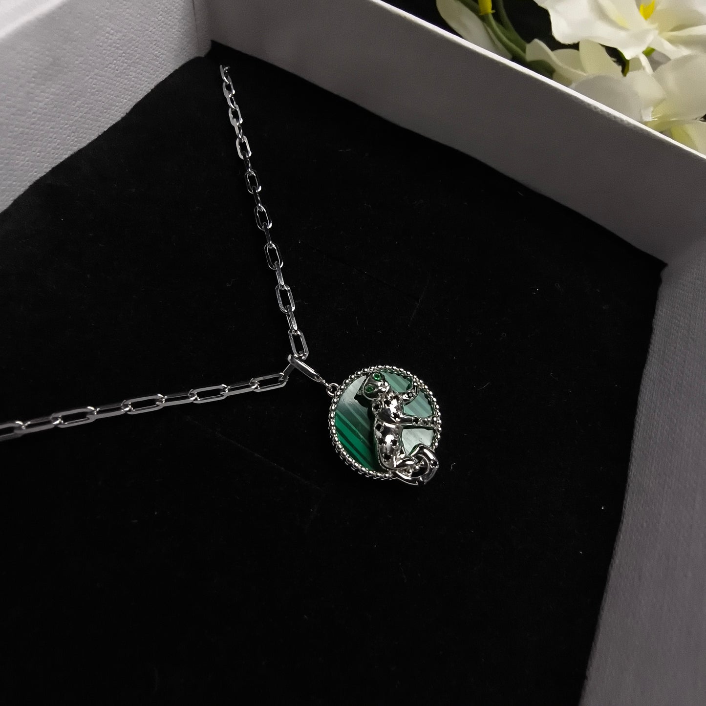 Silver necklace with a green stone in a box