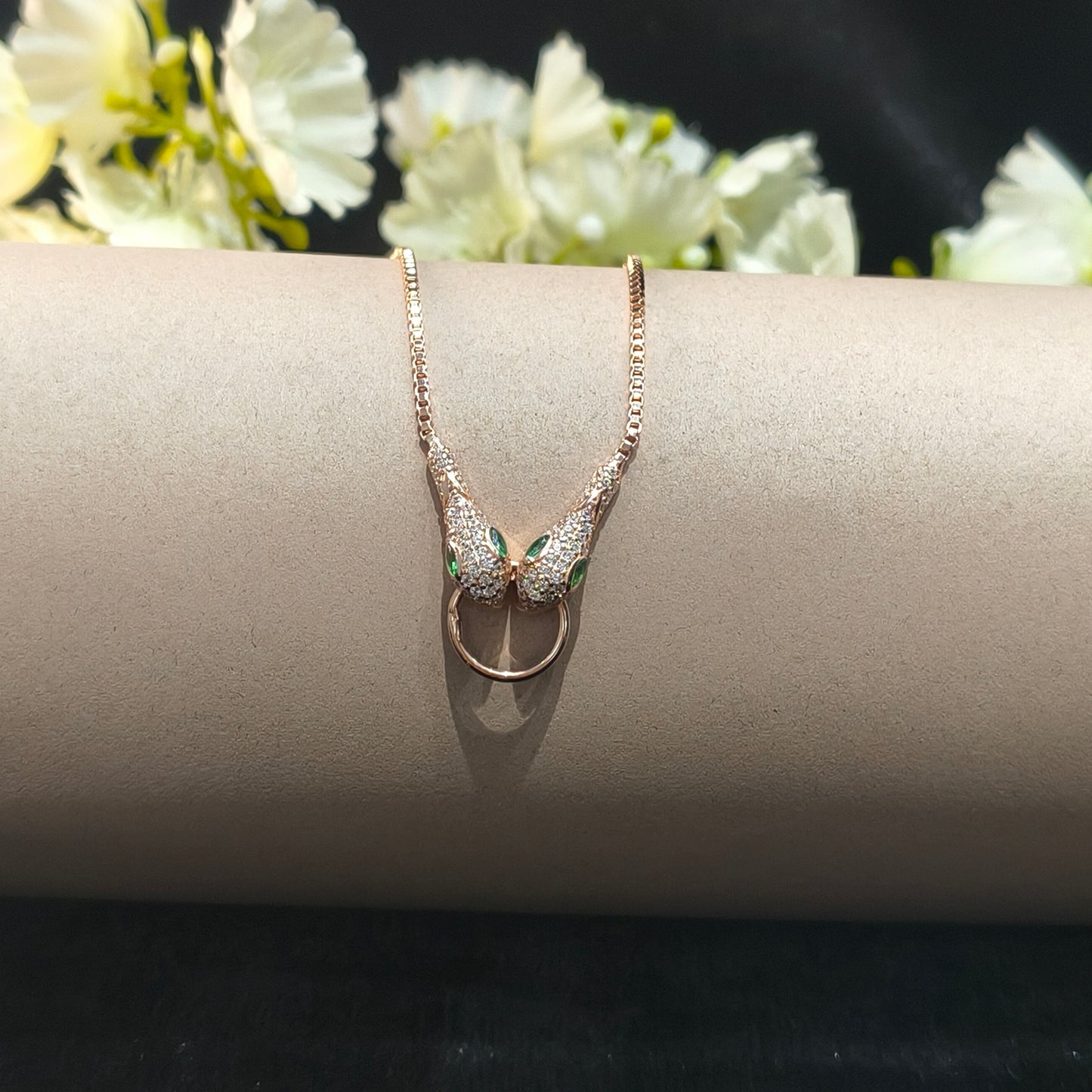 Silver bracelet on a gray stand with white flowers in the background