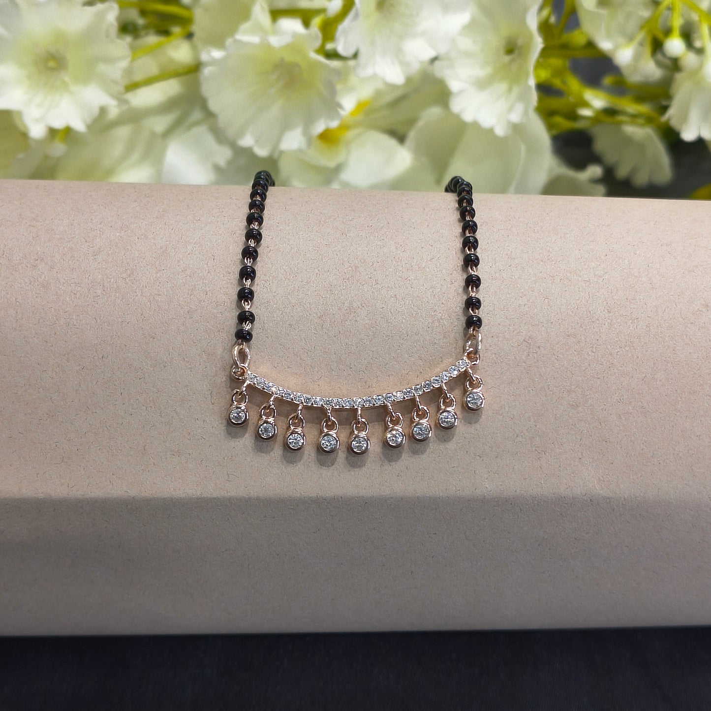 Bracelet with black and silver beads on a neutral background with flowers.
