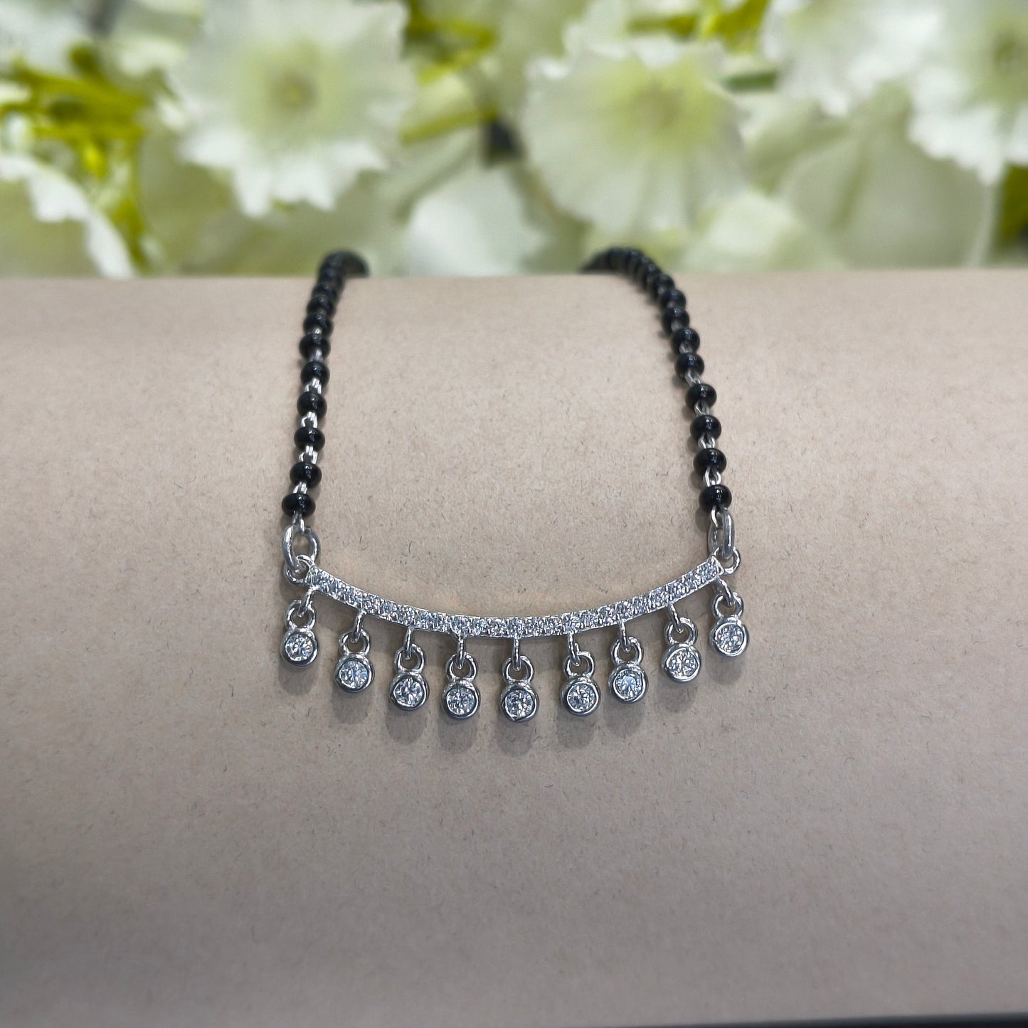 Two bracelets on a person's wrist with a floral background