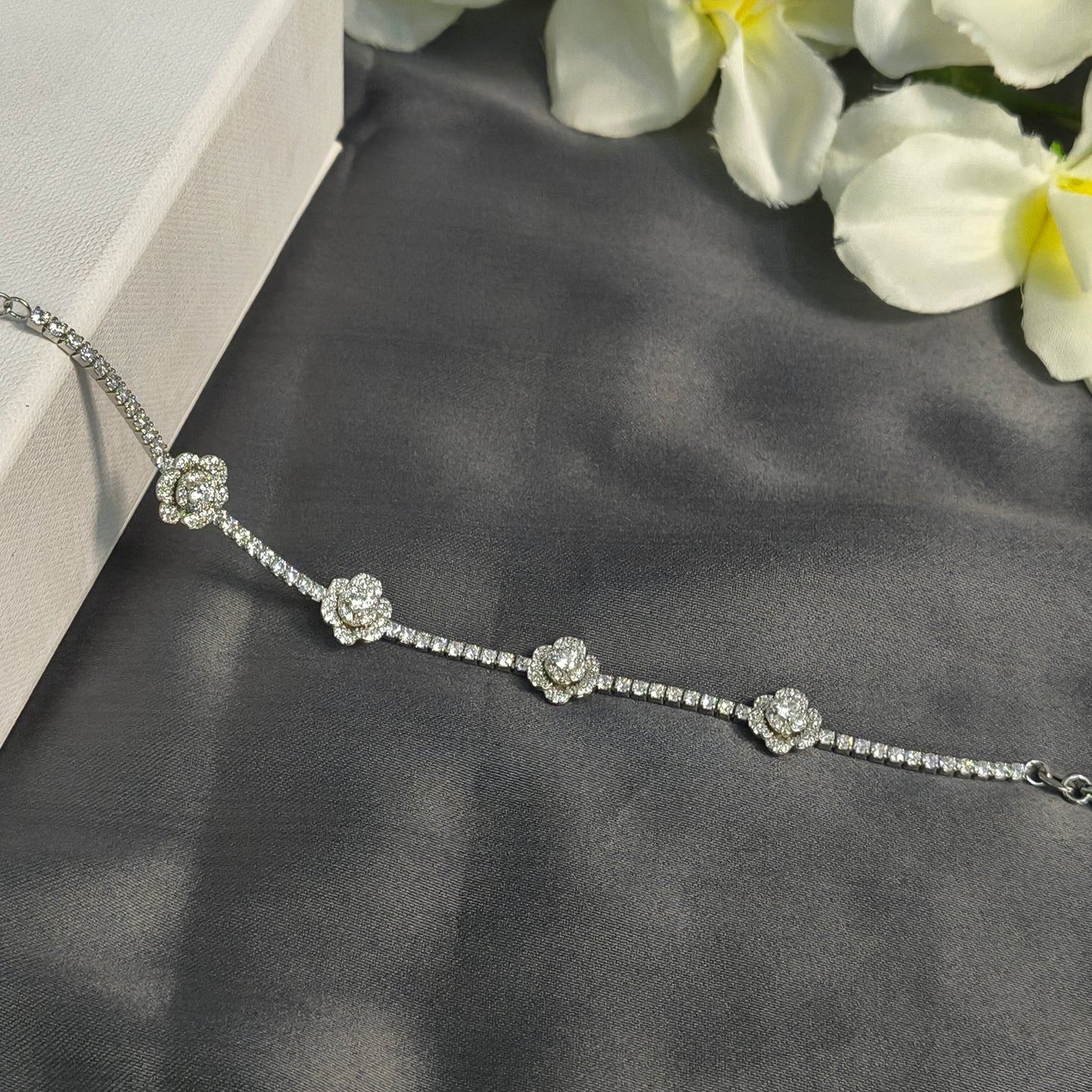 Silver bracelet with floral designs on a dark fabric background