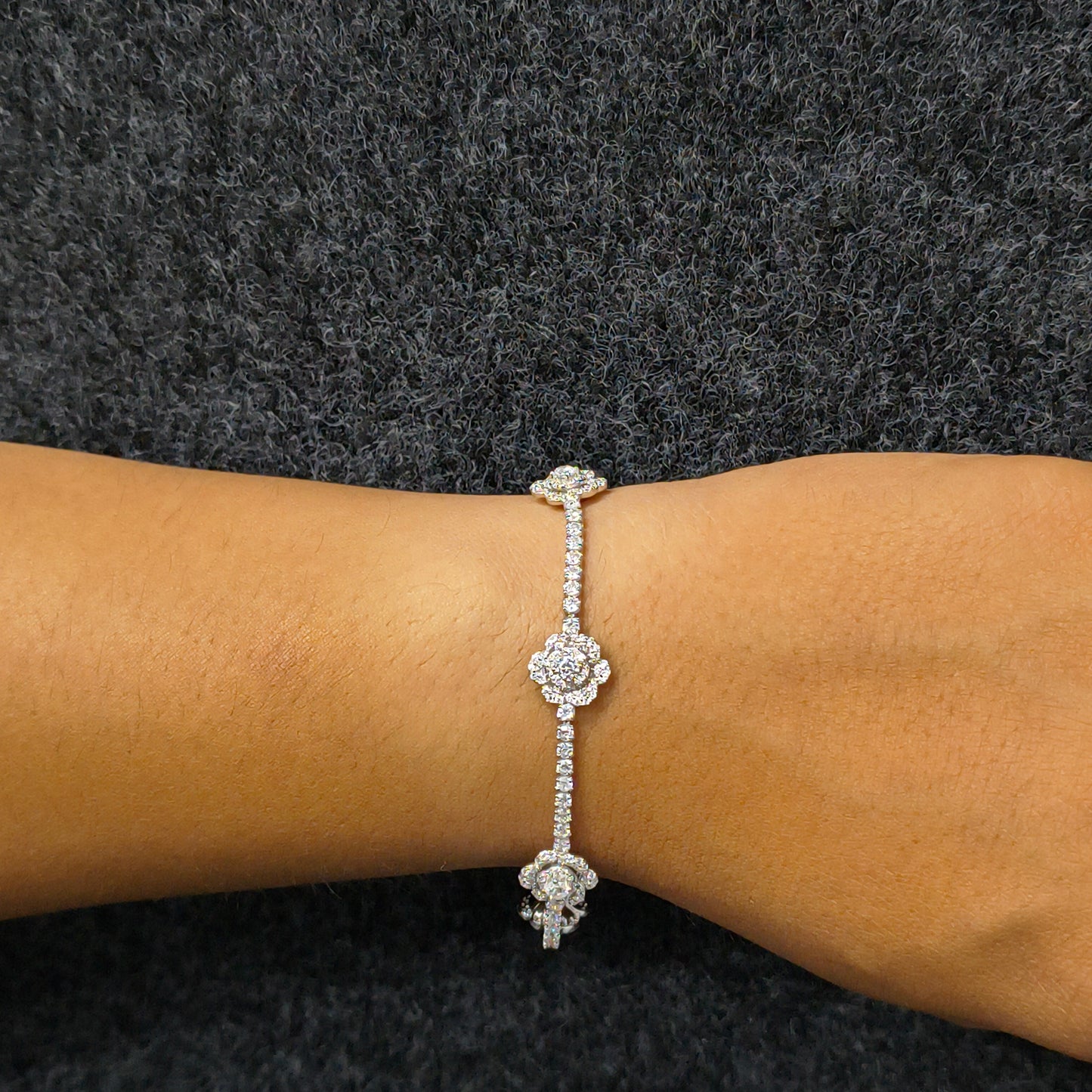 Silver bracelet with a floral design on a wrist against a dark background