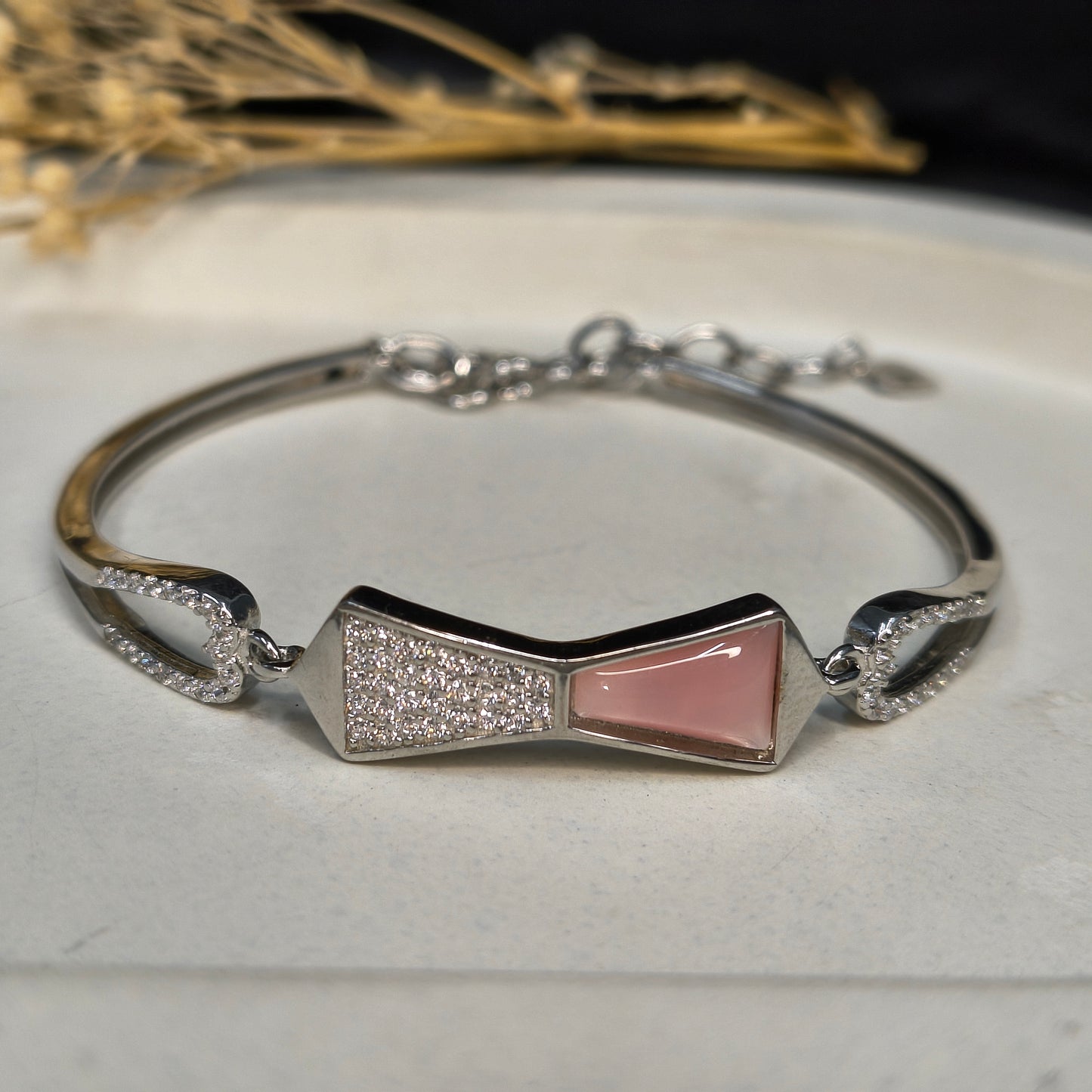 Silver bracelet with a pink gemstone on a light surface