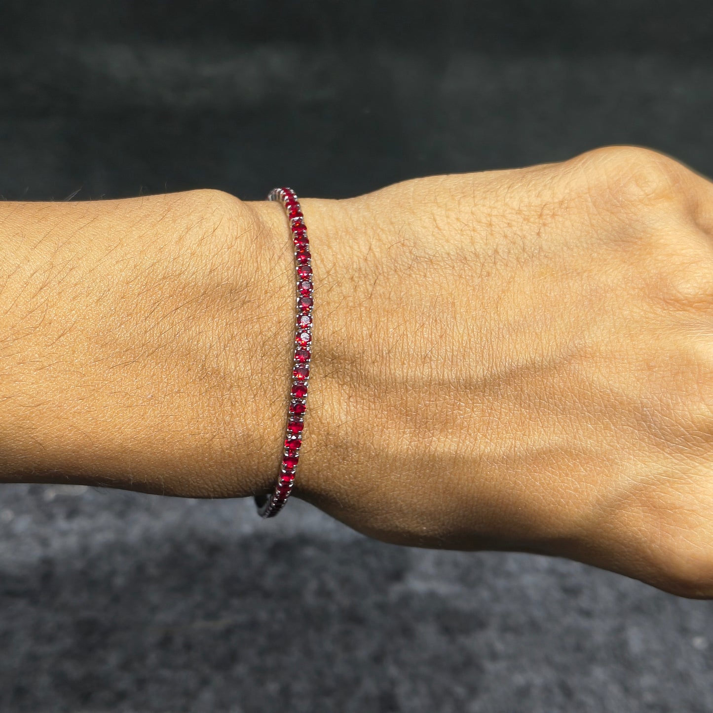 Close-up of a wrist wearing a red beaded bracelet against a dark background