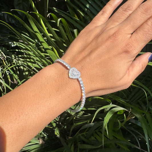 Hand wearing a diamond bracelet with a green leafy background