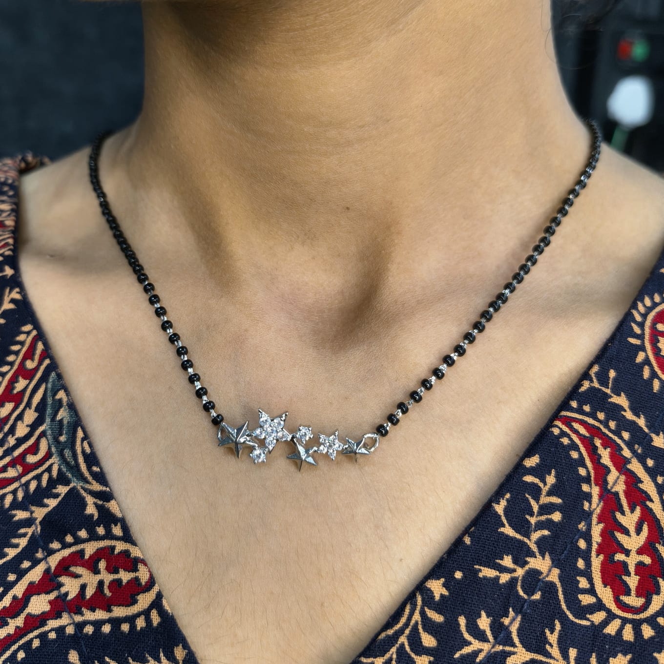 Necklace with a star-shaped pendant worn by a person against a patterned garment.