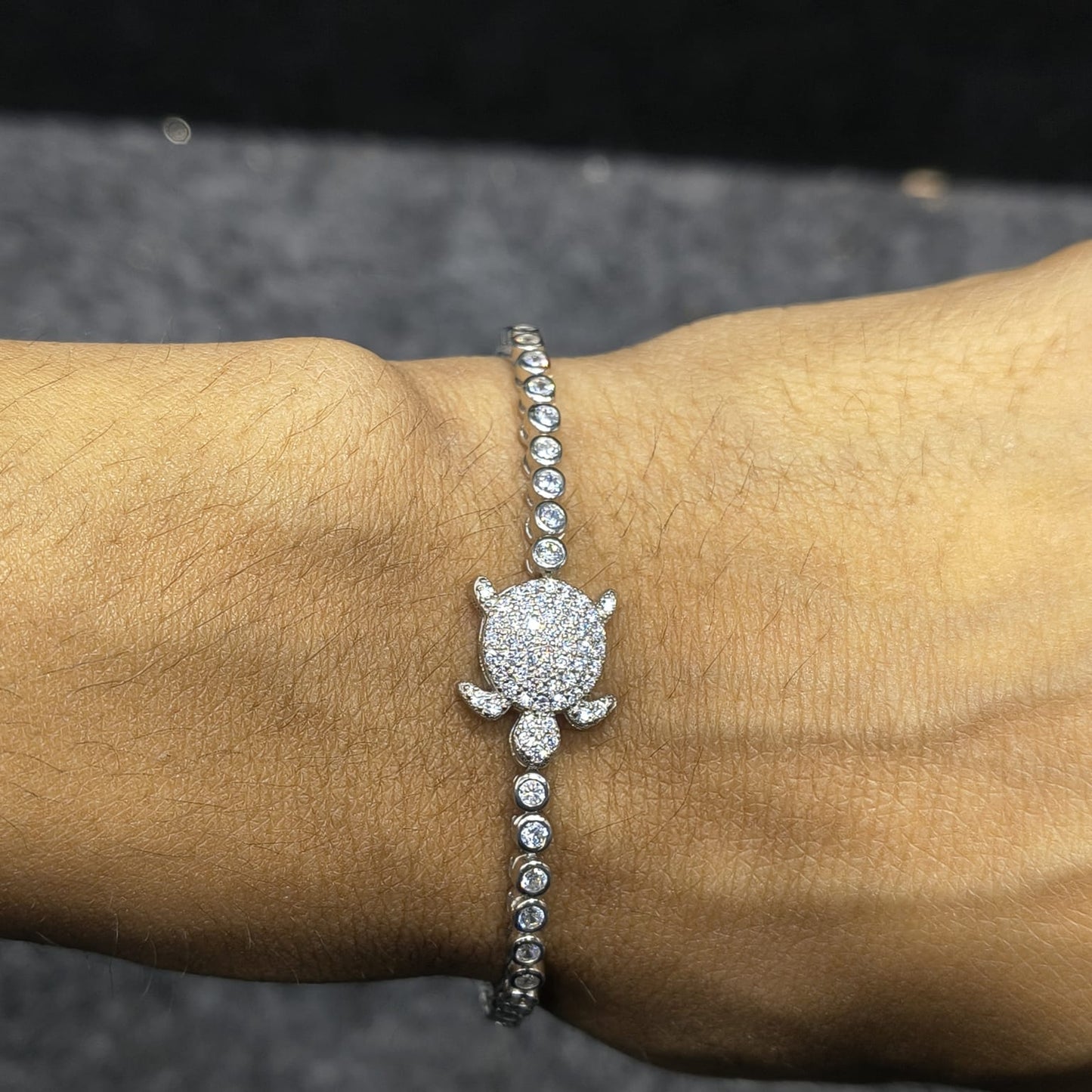 Silver bracelet with a large central gemstone on a wrist against a dark background