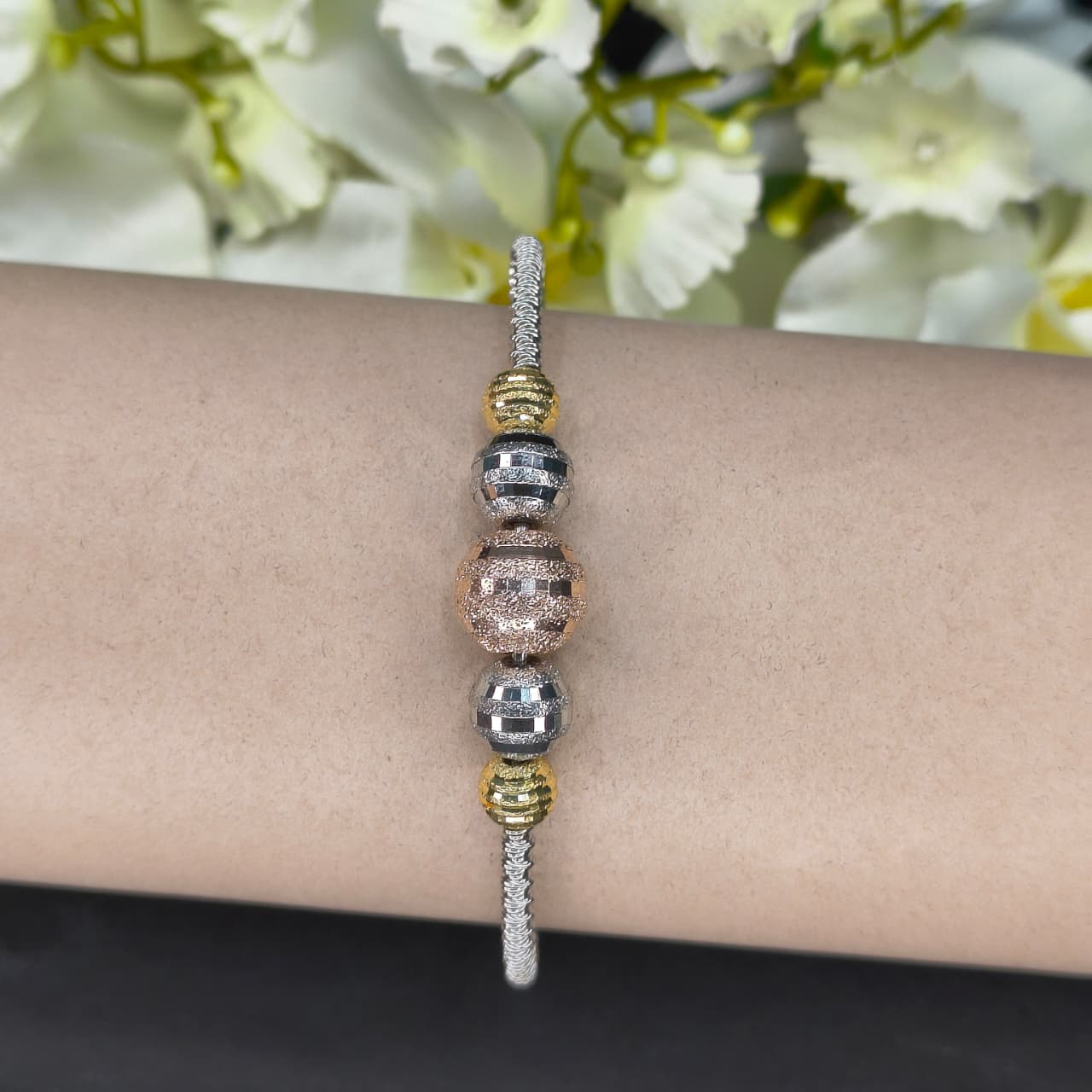 Bracelet with multicolored beads on a wrist against a floral background