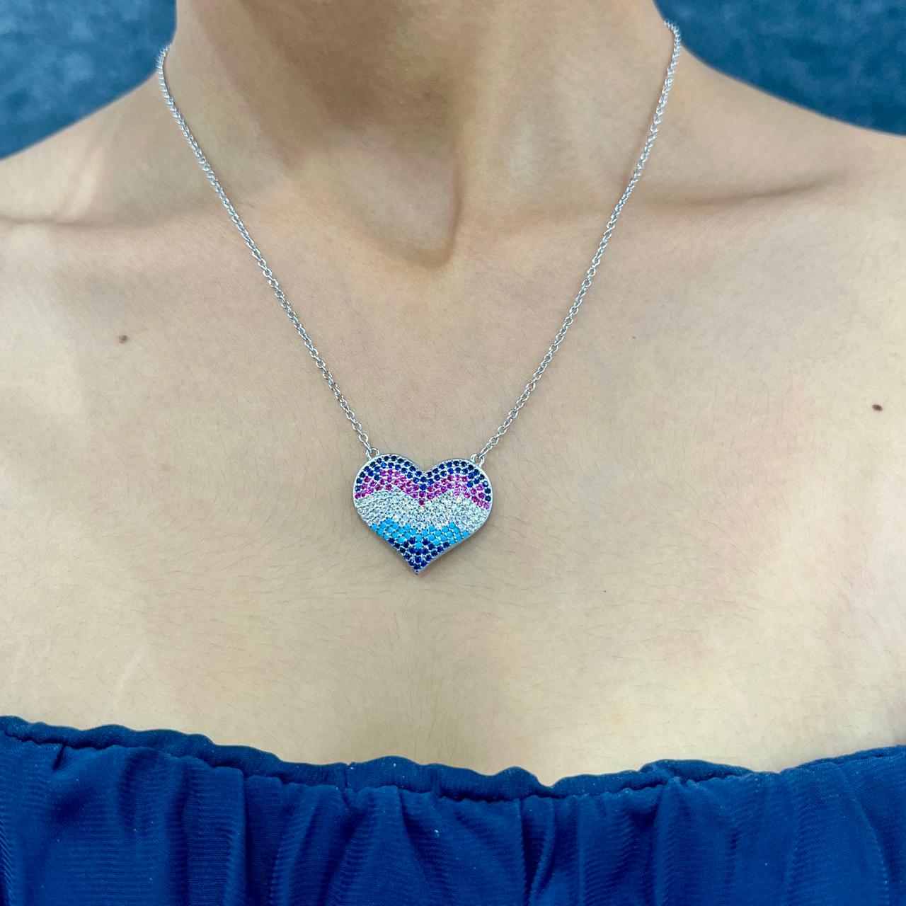 Necklace with a colorful heart-shaped pendant worn by a person against a blue background