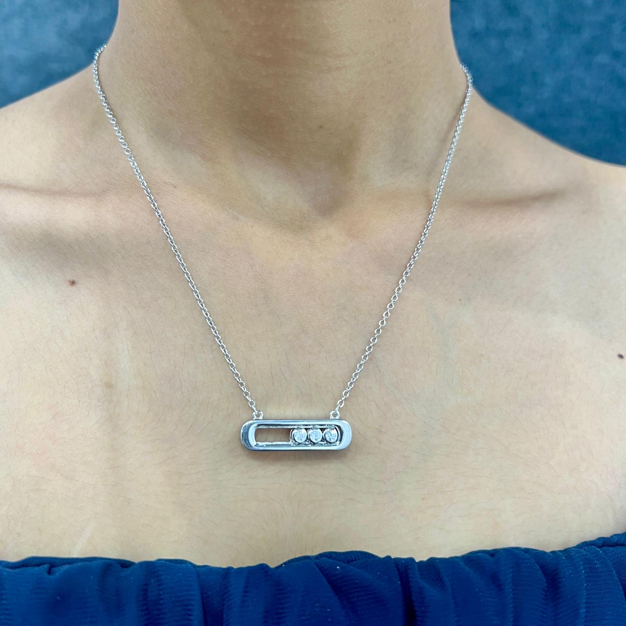 Silver necklace with a pendant on a person wearing a blue top against a blue background