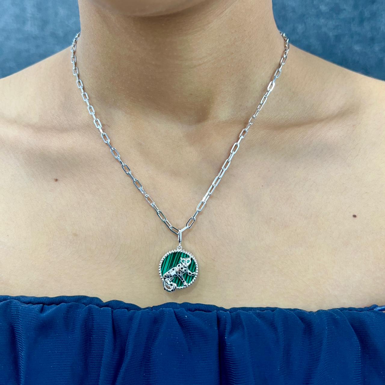 Necklace with a green pendant worn by a person against a blue background