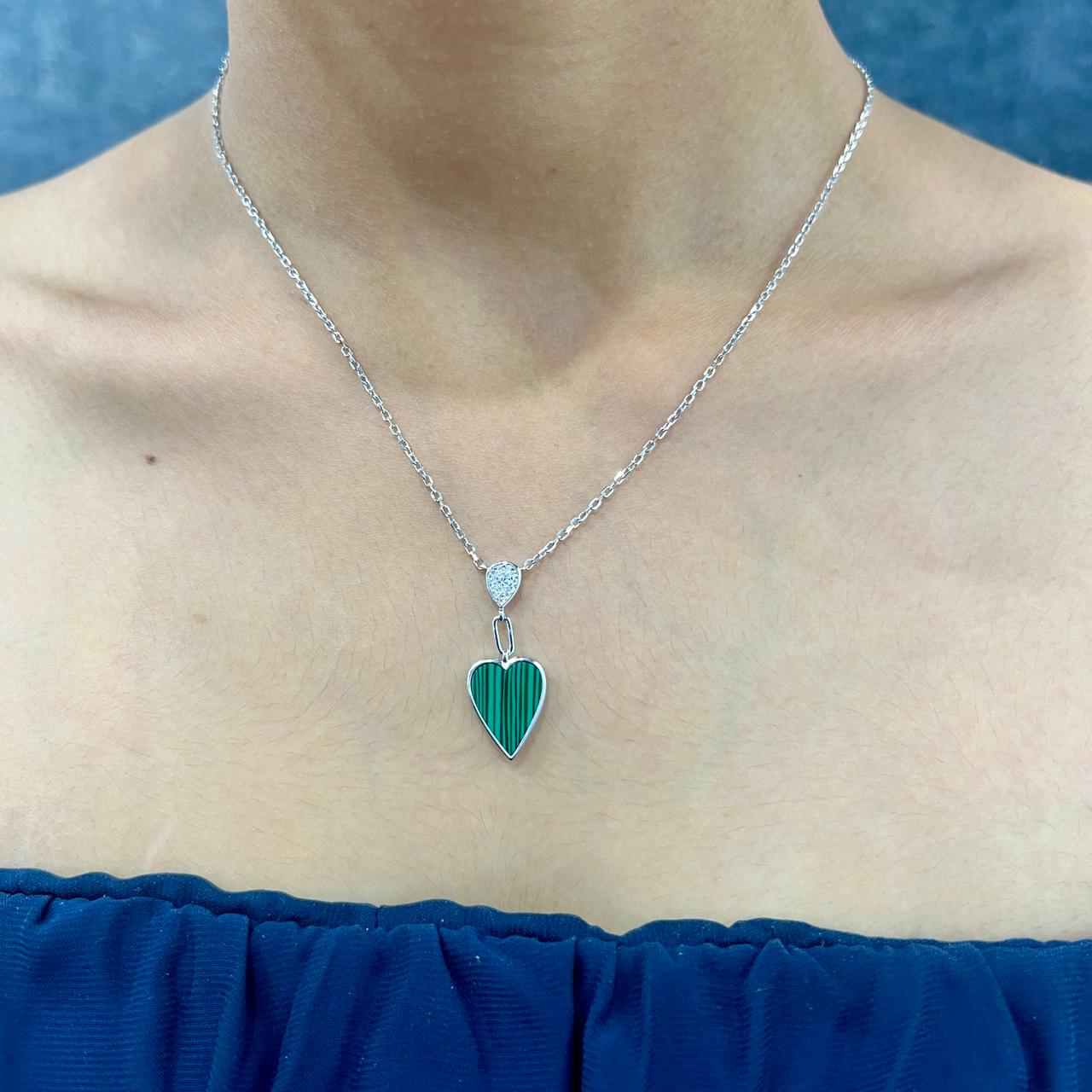 Necklace with a green heart pendant worn by a person against a blue background