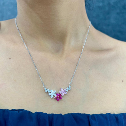 Necklace with floral design and gemstones worn by a person against a blue background