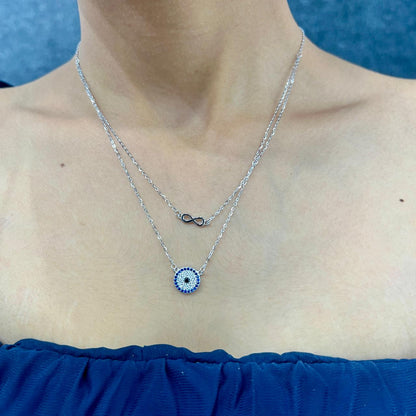 Silver necklace with a blue and white pendant worn by a person against a blue background