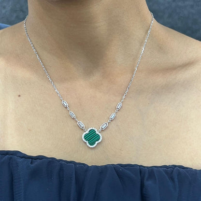 Necklace with a green pendant worn by a person against a dark background