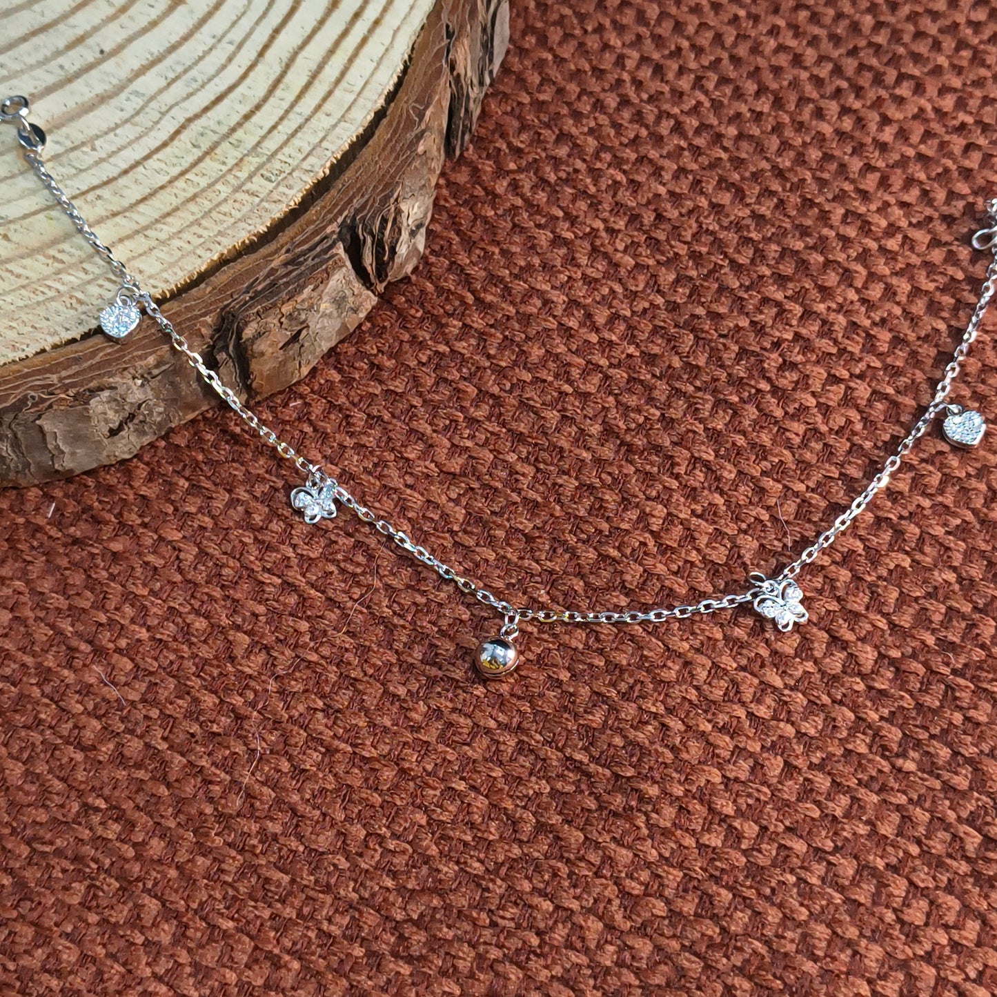 Silver necklace with small pendants on a brown textured surface