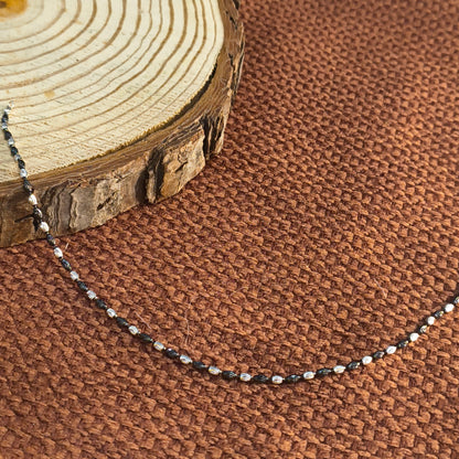 Close-up of a necklace with a wooden pendant against a brown textured fabric background