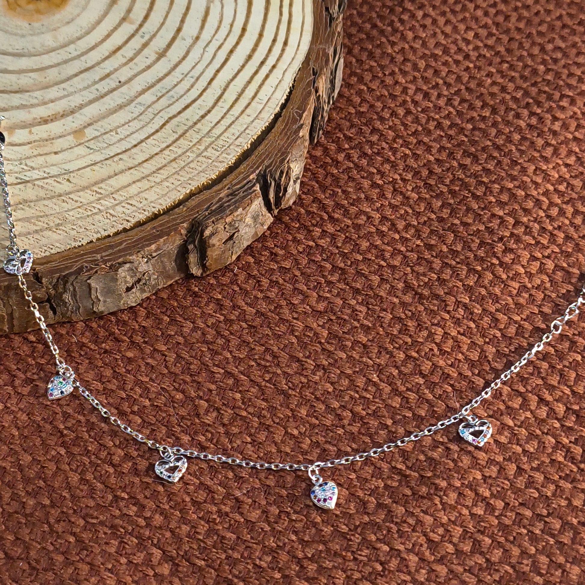 Delicate silver necklace with small crystals on a brown textured surface