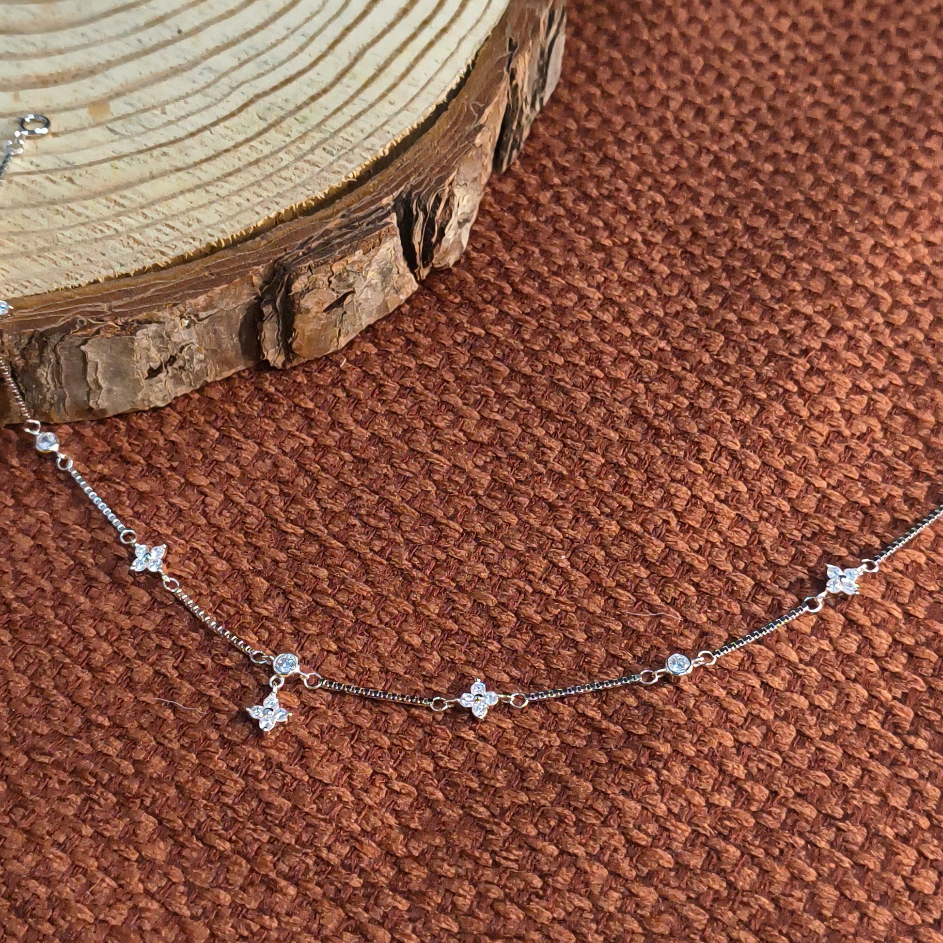 Silver necklace with star-shaped pendants on a brown textured fabric background