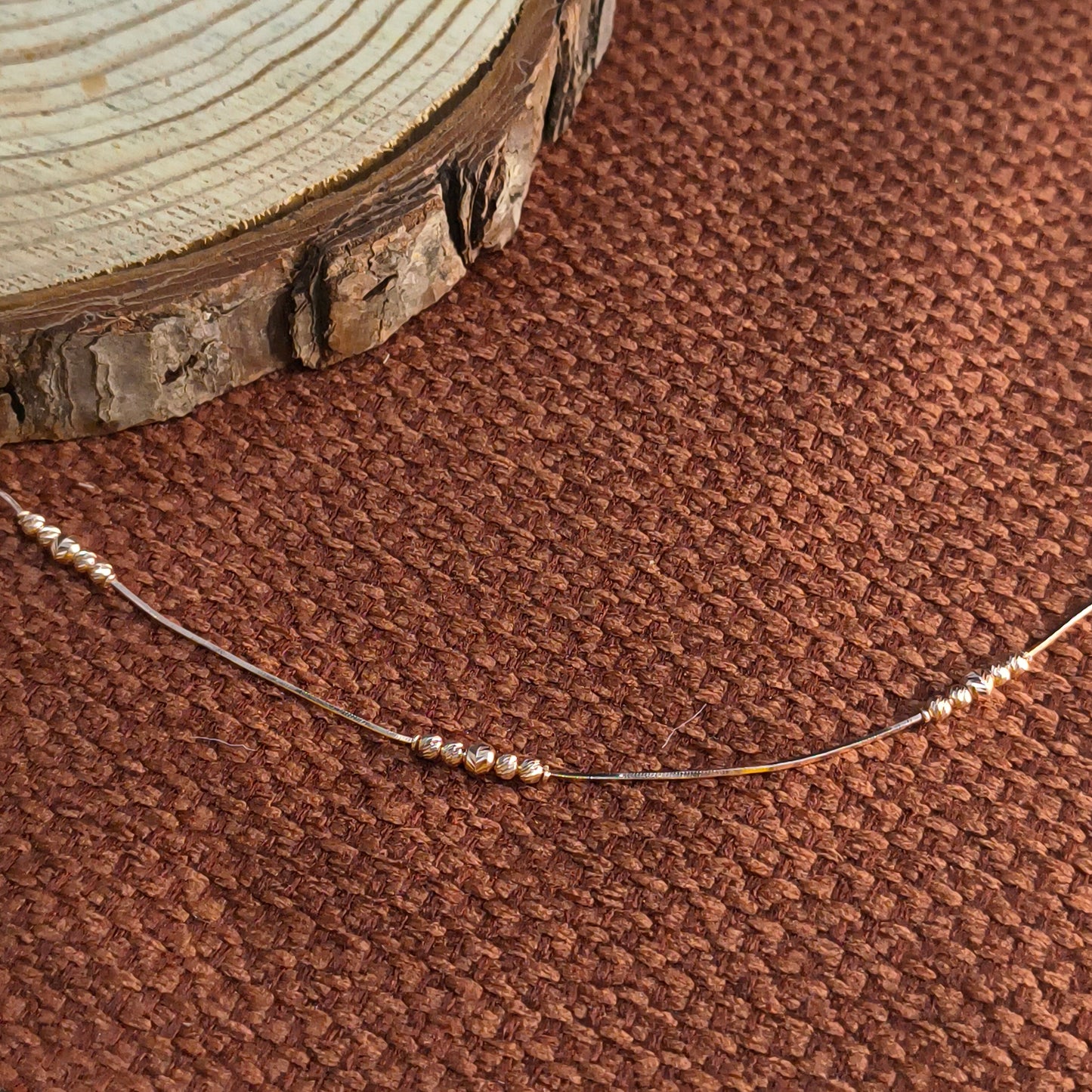 Close-up of a beaded necklace on a brown textured fabric background