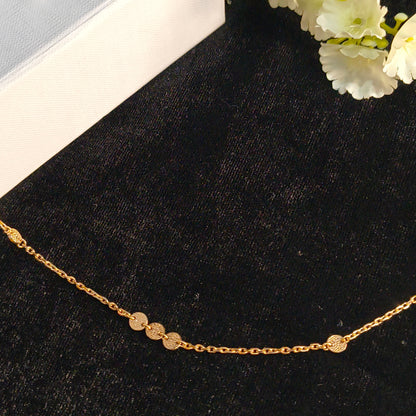 Gold necklace on a black surface with white flowers