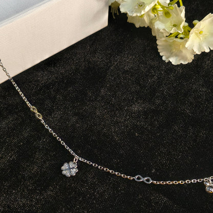 Necklace with a floral pendant on a black surface with white flowers.