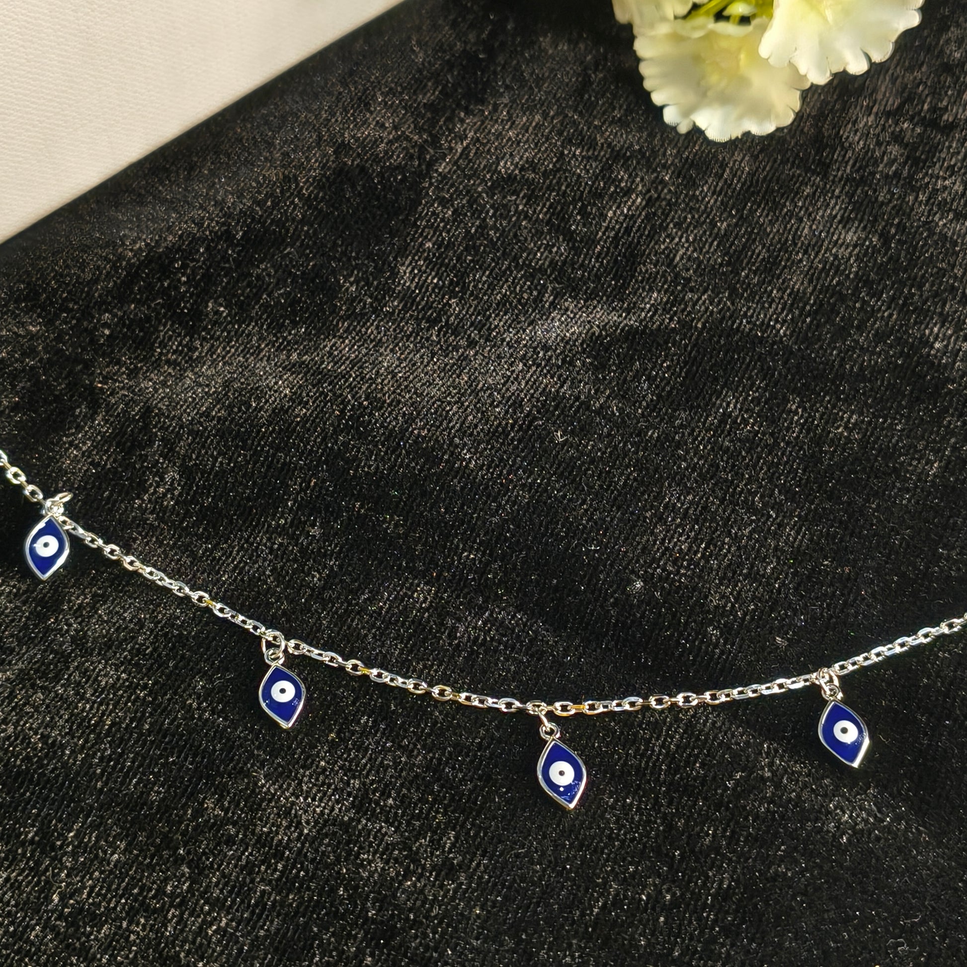 Silver bracelet with eye-shaped charms on a dark textured surface