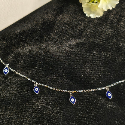 Silver bracelet with eye-shaped charms on a dark textured surface