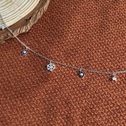 Silver necklace with eye and star charms on a brown textured surface