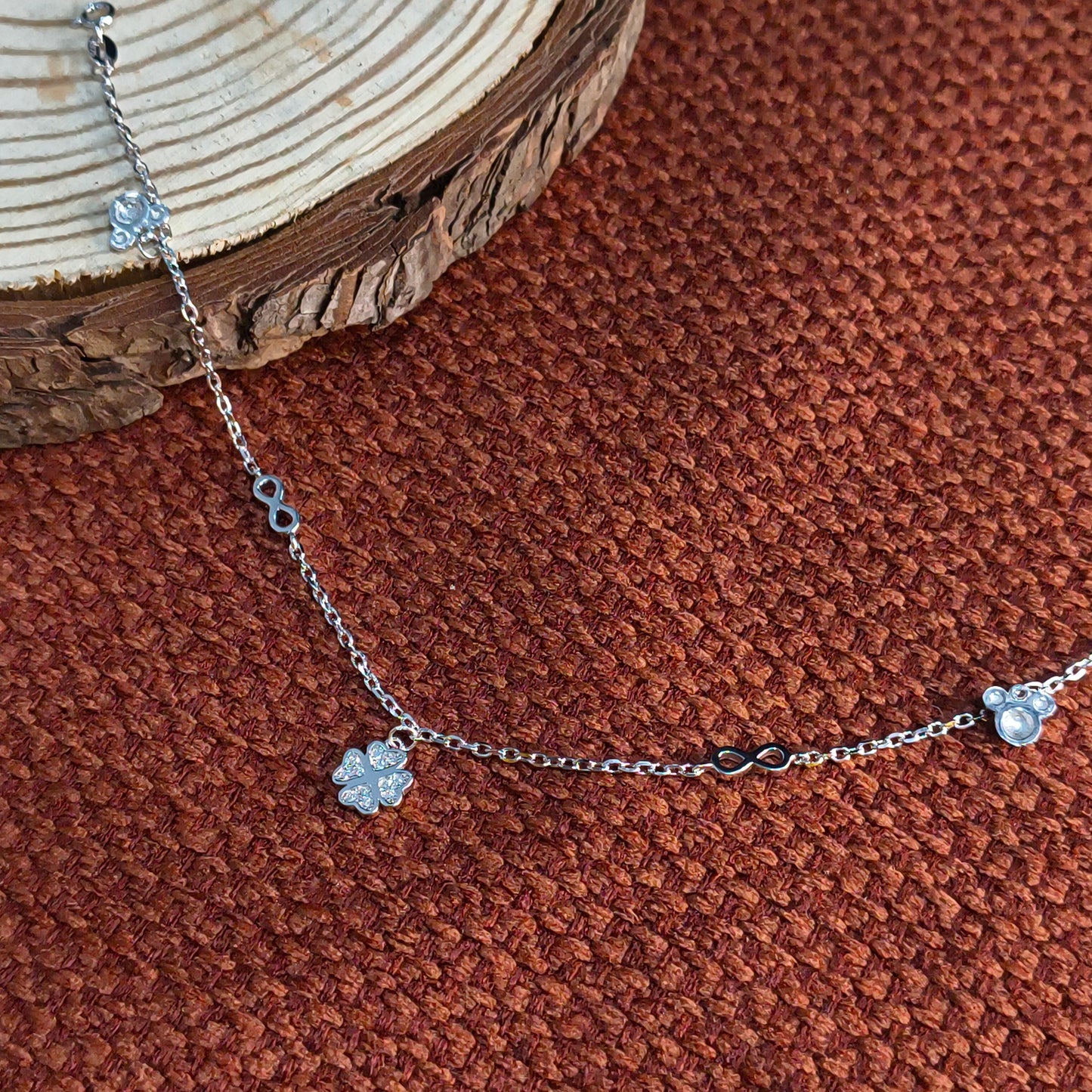Silver bracelet with floral charms on a brown textured surface