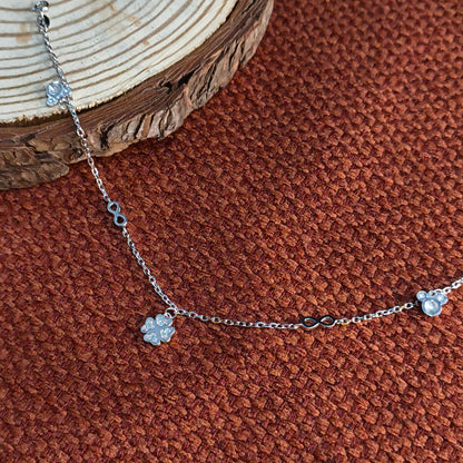 Silver bracelet with floral charms on a brown textured surface