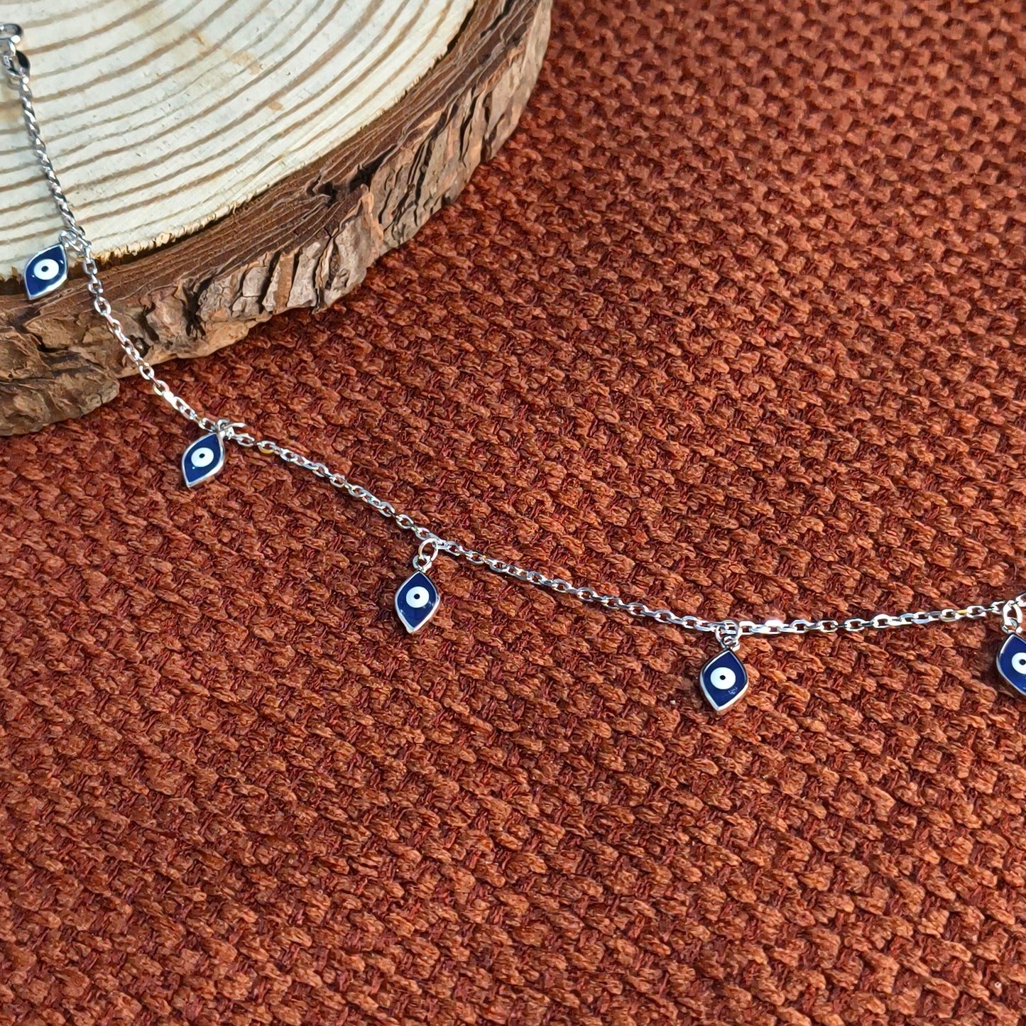 Silver necklace with blue eye-shaped charms on a brown textured surface