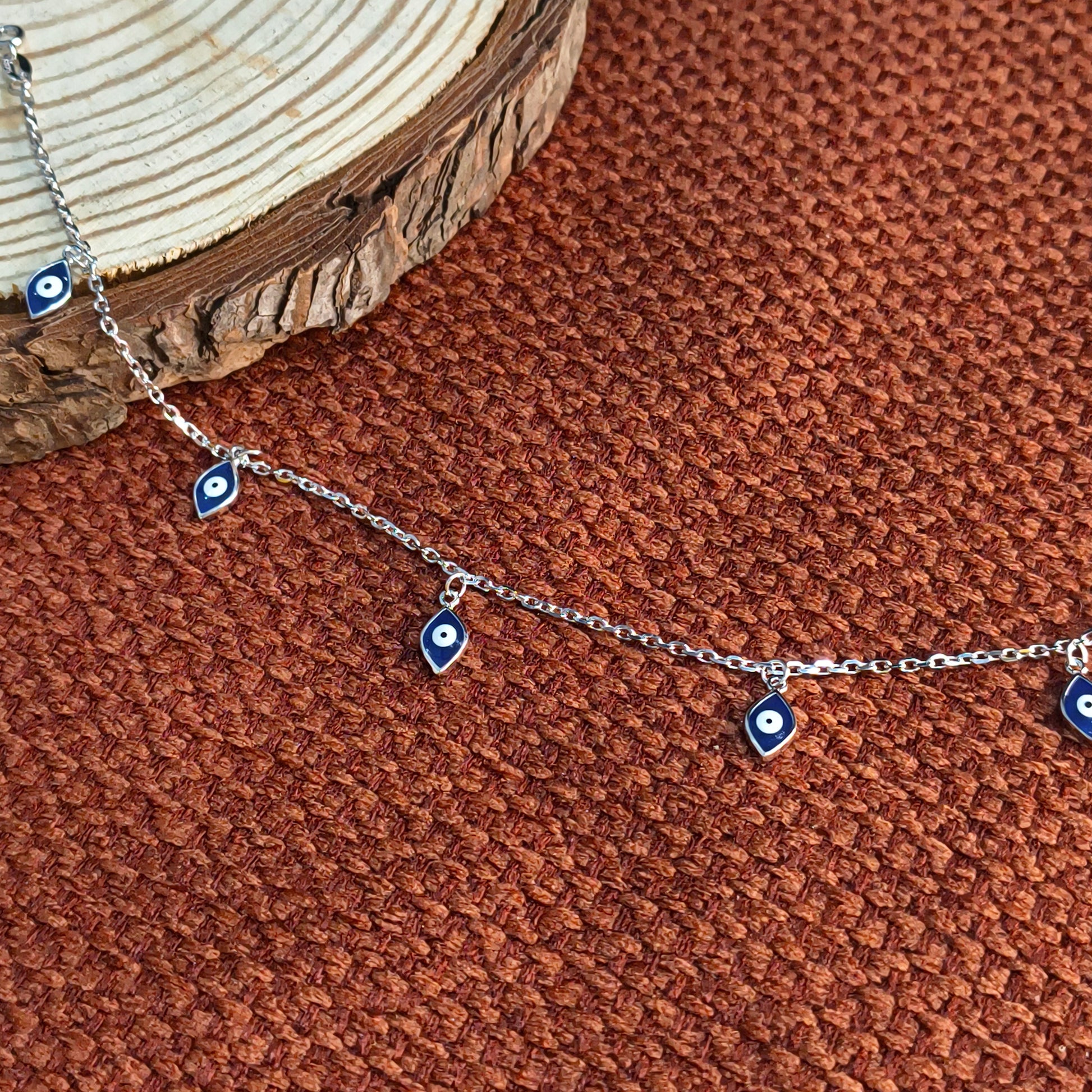 Silver necklace with blue eye-shaped charms on a brown textured surface
