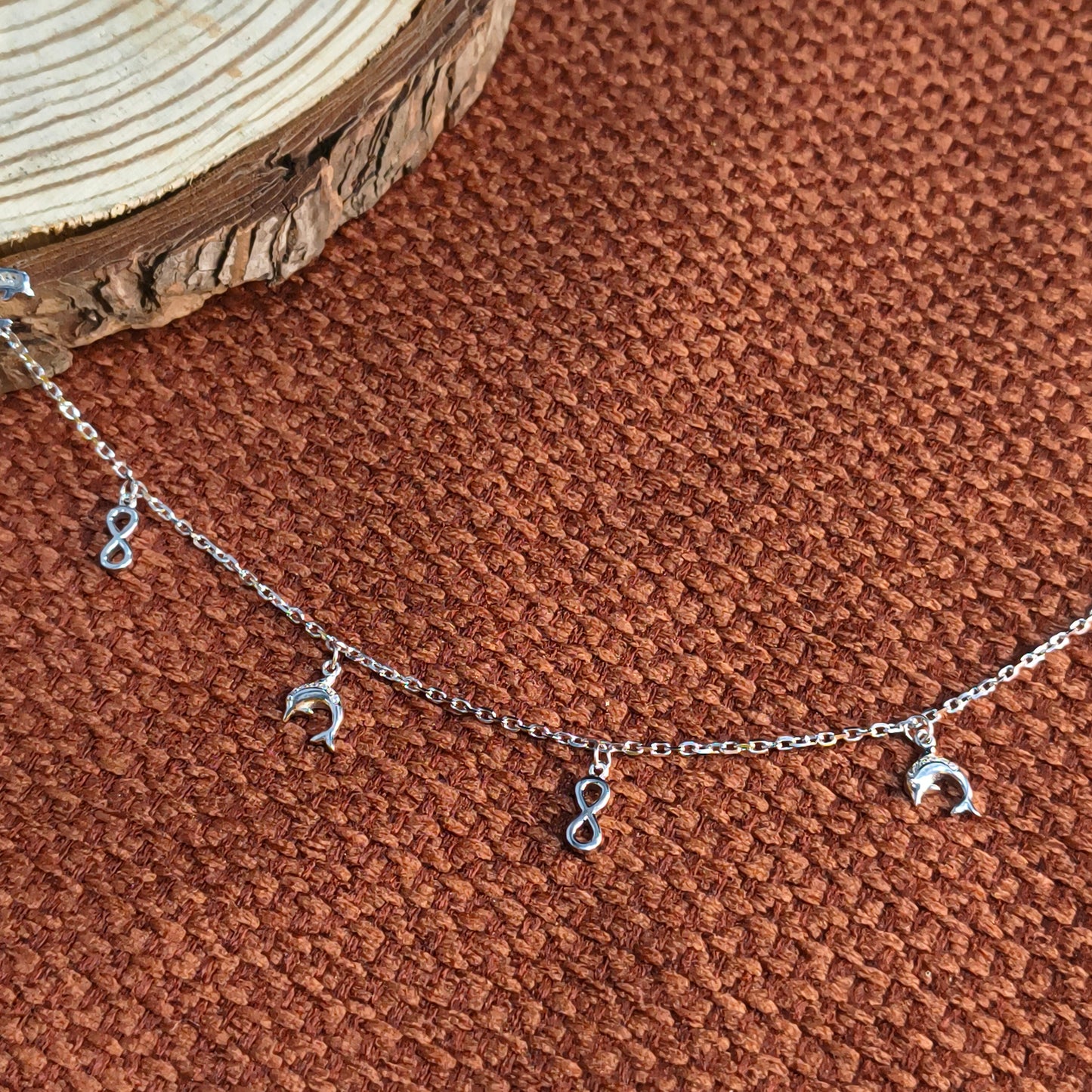 Silver bracelet with moon-shaped charms on a brown textured surface