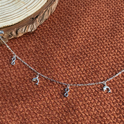 Silver bracelet with moon-shaped charms on a brown textured surface