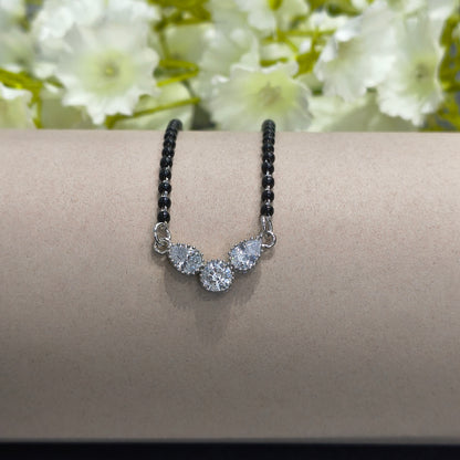 Bracelet with black beads and silver floral charm on a wrist against a floral background