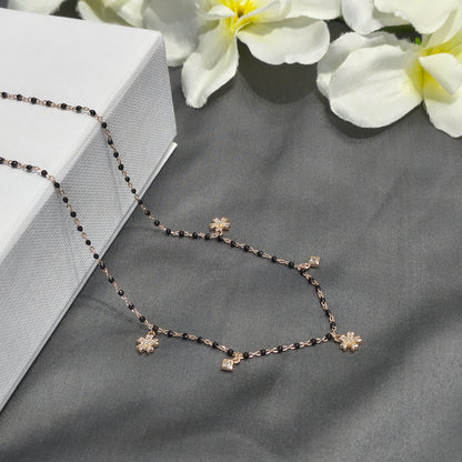 Necklace with floral pendants on a gray surface with white flowers in the background