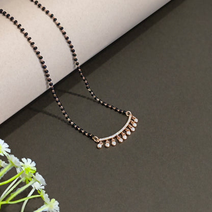 Jewelry with black beads and gold accents on a dark surface with flowers.