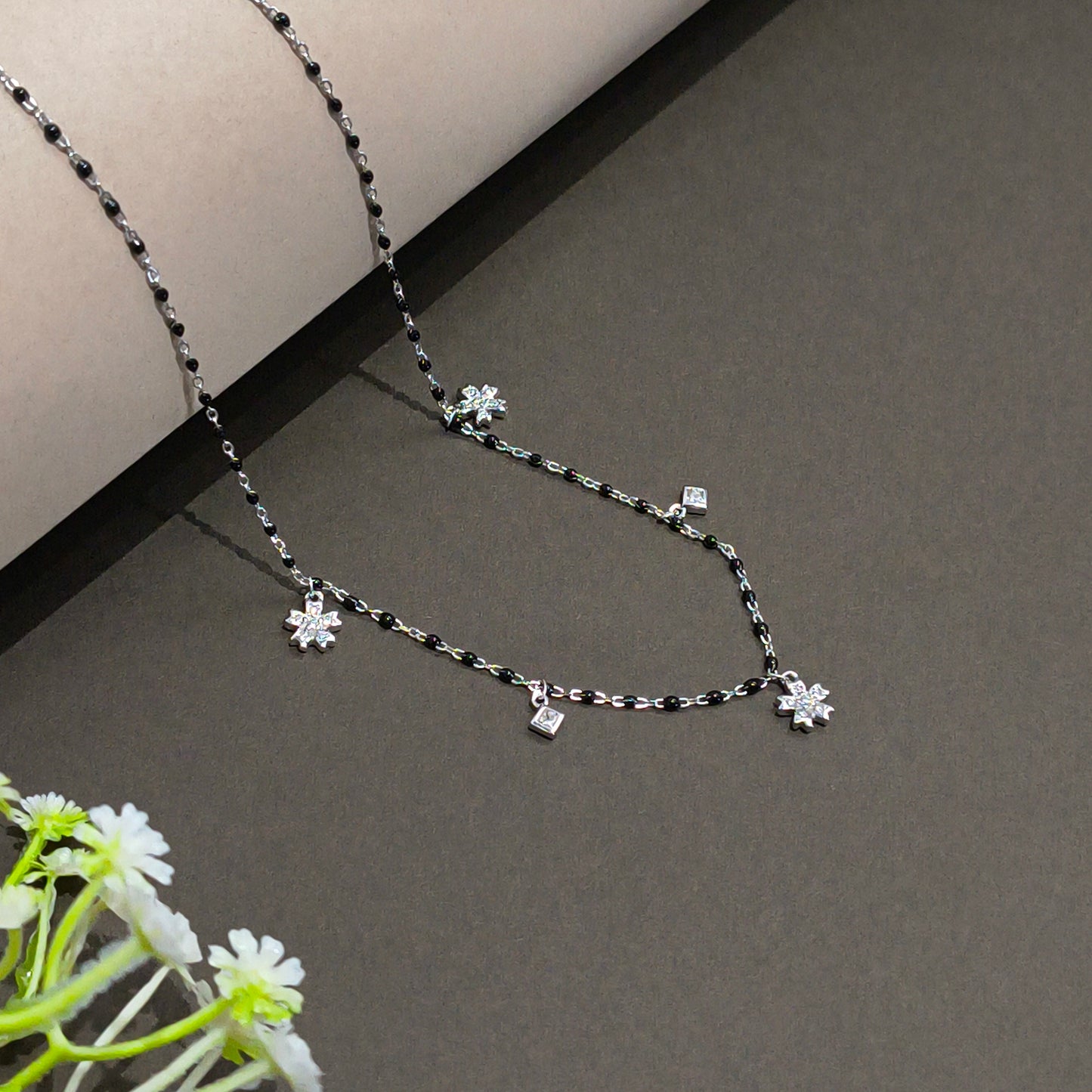 Silver necklace with floral pendants on a gray background