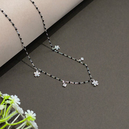 Silver necklace with floral pendants on a gray background