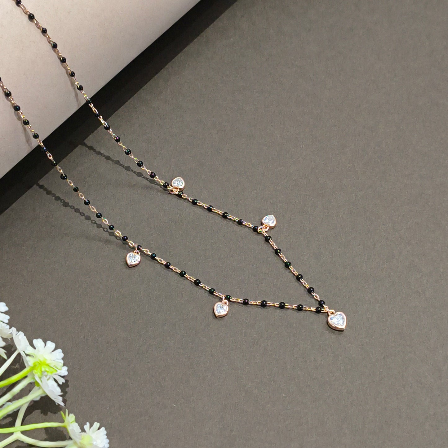 Delicate necklace with black and gold chain on a gray background