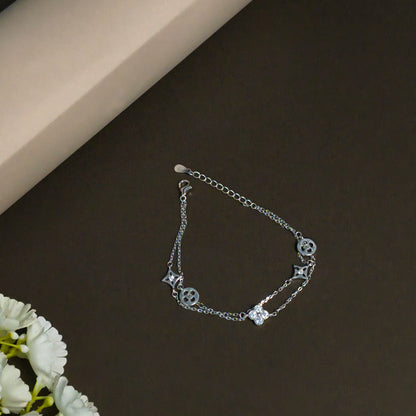 Silver bracelet with star and heart charms on a dark surface with a light background