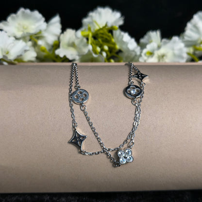 Silver bracelet with star-shaped charms on a cylindrical object with white flowers in the background