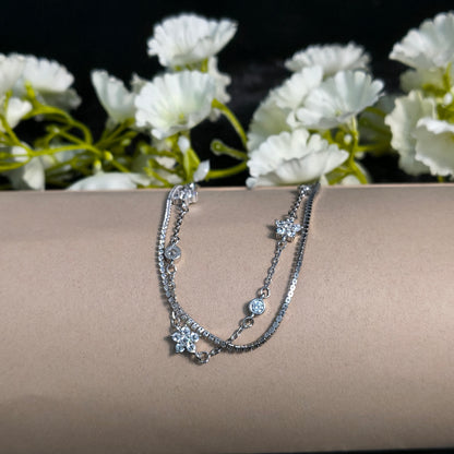 Silver bracelet on a mannequin arm with white flowers in the background